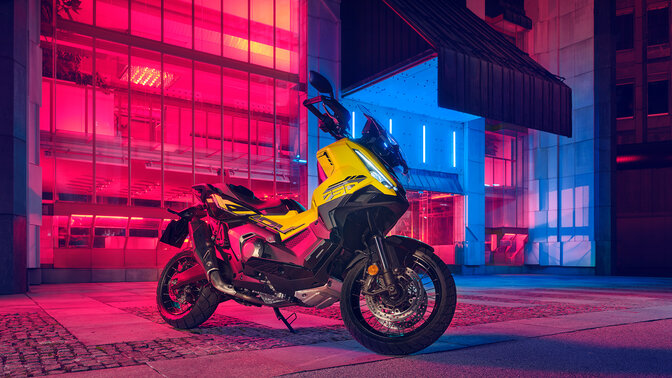 Trojštvrťový statický záber spredu na skúter X-ADV Special Edition s budovou na pozadí